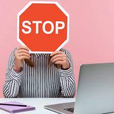 Una persona sujeta una señal de Stop delante de su cara en señal de terminar con el acoso laboral.